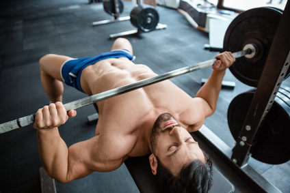 Portrait of a handsome muscular man doing bench press in fitness gym
